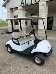 A white golf cart parked in front of a building.